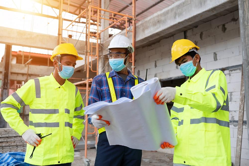 three workers looking at a large plan on paper