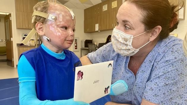 Avery has been in good hands at Shriners Children’s Ohio, which provides life-changing burn and plastic surgery care, regardless of families’ ability to pay or their insurance status. Avery and a medical professional smiling at each other. The child holds a card with "Avery" on it.