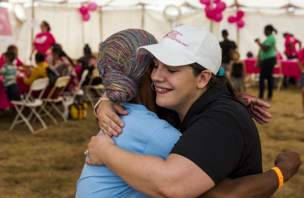 A photo of two women hugging at a Breast Cancer Awareness event