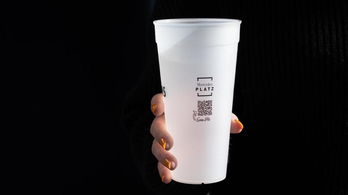 Hand holding reusable cup from Mercedes-Benz Arena.
