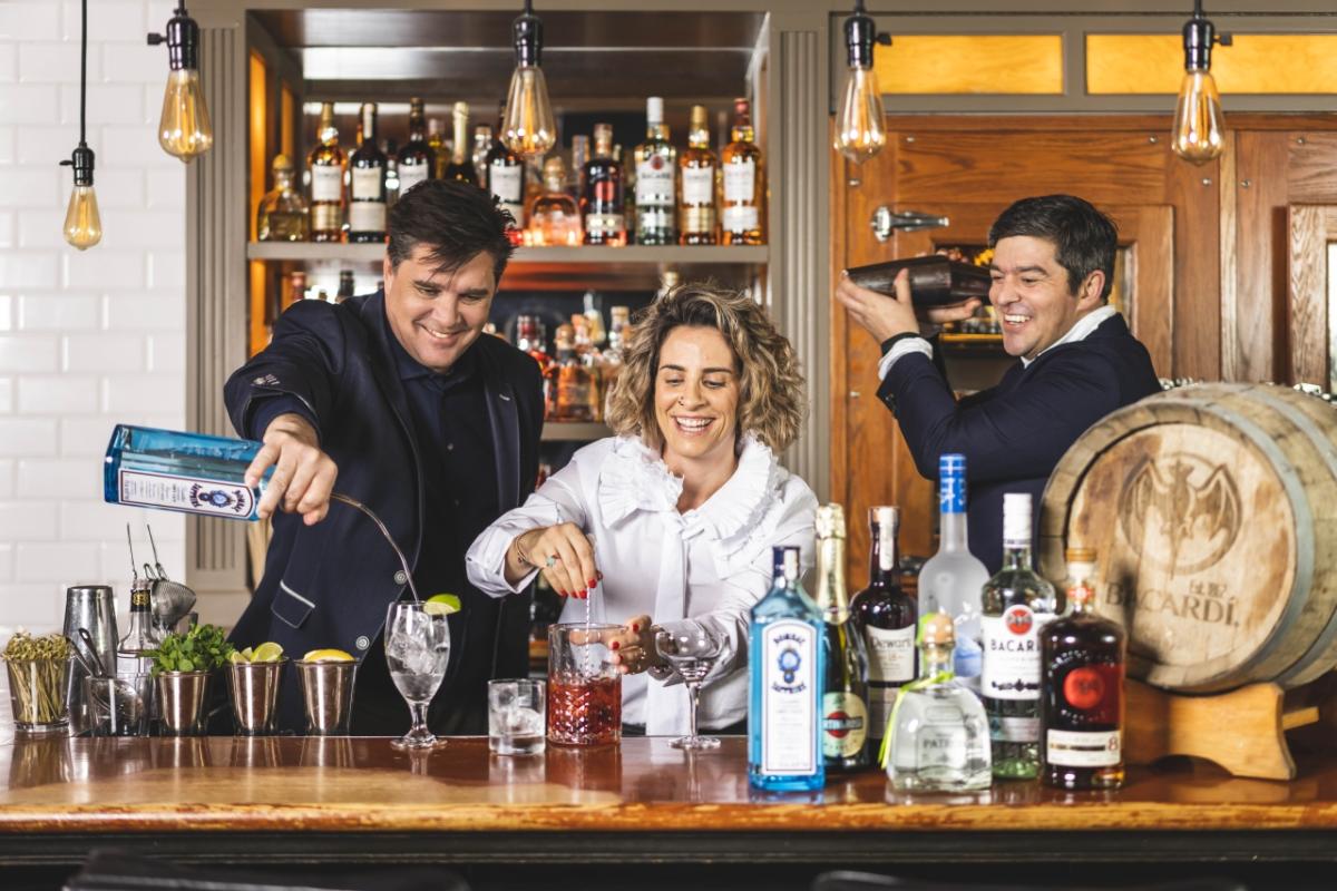 3 Bartenders smile while making drinks