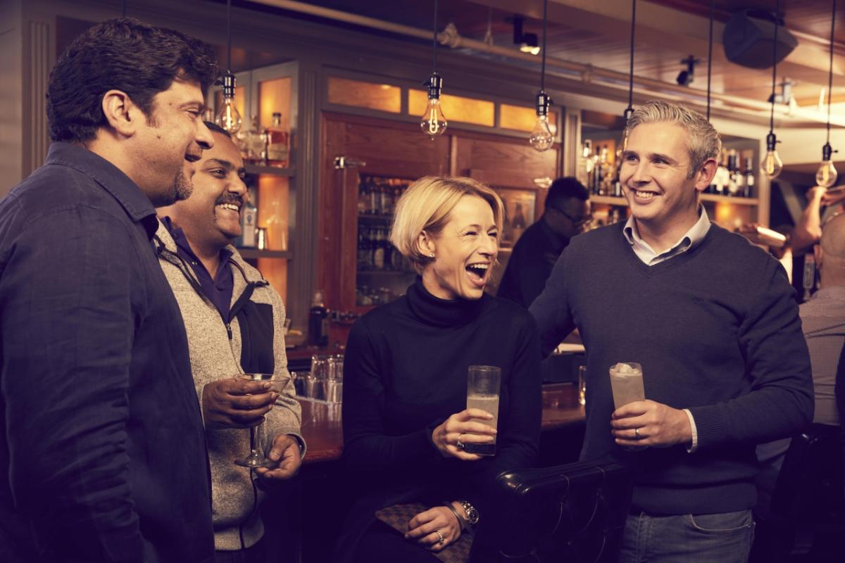 4 people enjoy drinks at a bar