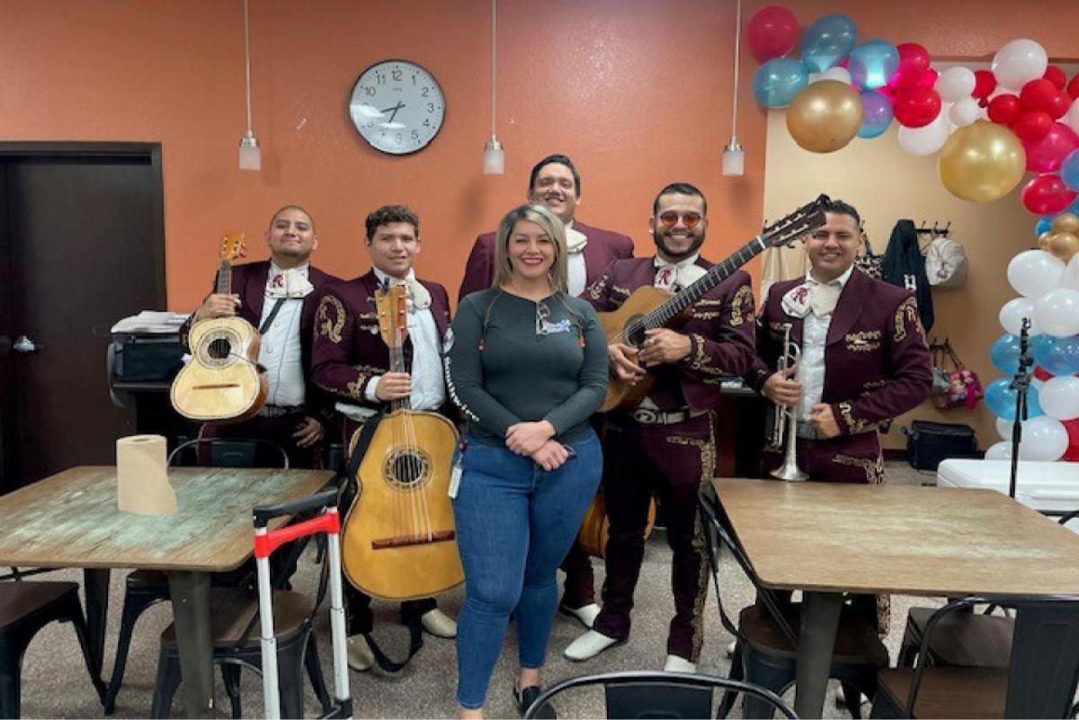 An employee standing with a mariachi band in a break room.