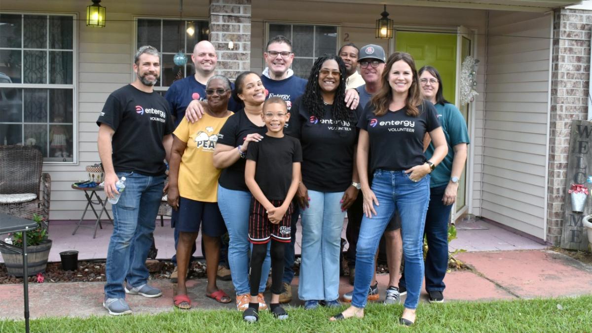 A group of people posed outside a home.