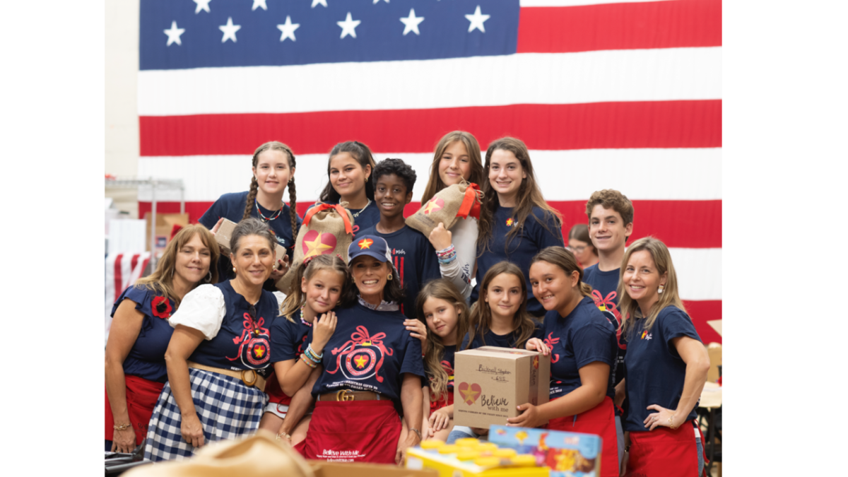 Group posing with boxes in front of an American flag