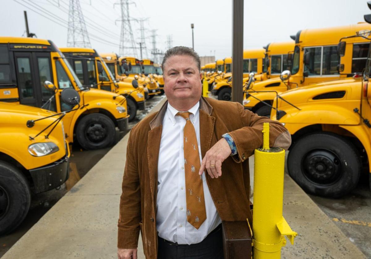 Man posing with school buses