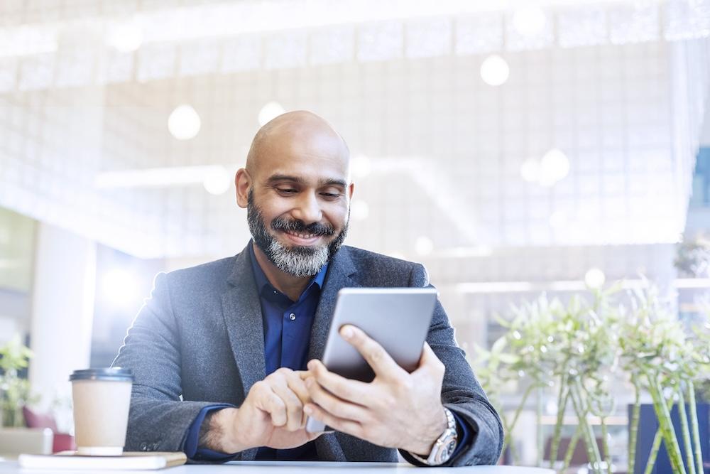 Man seated at a table with a tablet.