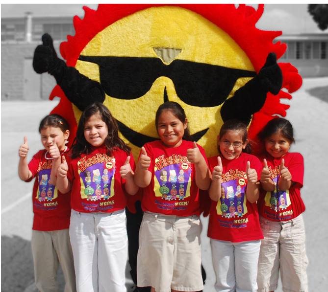 Five children in matching t-shirts give 'thumbs-up'. A Bienstar mascot behind them.