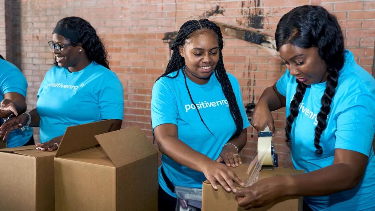 NRG volunteers sealing a box for Bread of Life donations.