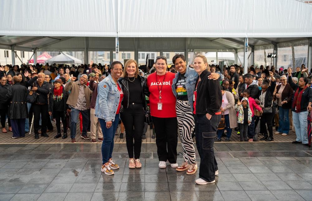 Five people standing together in front of cheering crowd
