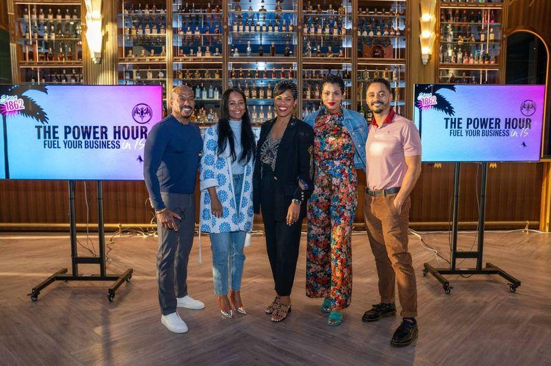 Five people posing next to a sign that reads "power hour: fuel your business in 15"