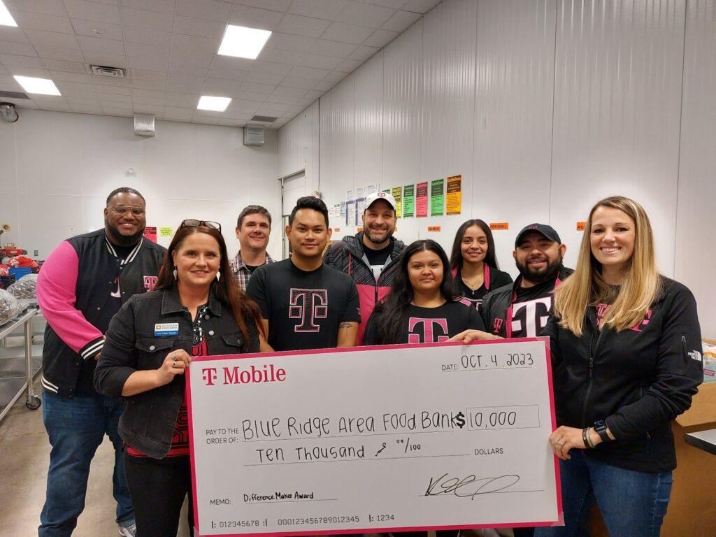 A group of people posed with a large check in an open room.