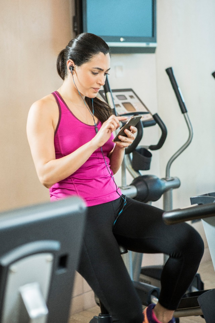 Booz Allen Associate Diana Menhem checks her phone while on an exercise bike at a gym in Dubai, UAE.