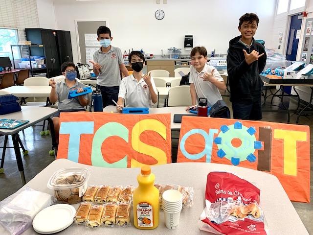 A small group in a classroom holding a TCS goIT sign.