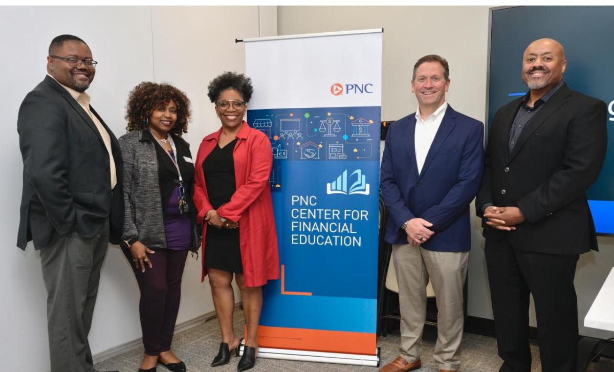 A small group of people stood either side of a PNC Center for Financial Education event banner