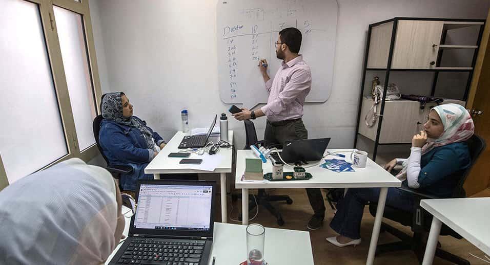 people working with one writing on a whiteboard