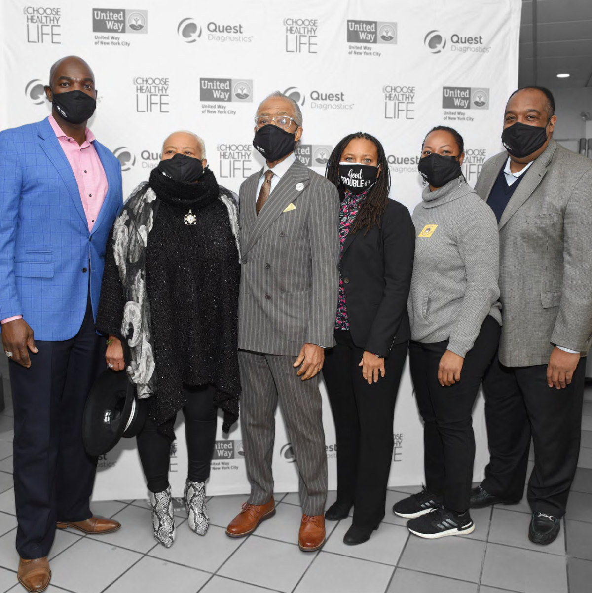 a group of six people stand in front of a wall of logos for choose healthy life, quest diagnostics and united way