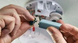 Close up of someone connecting a battery to a CO2 detector.