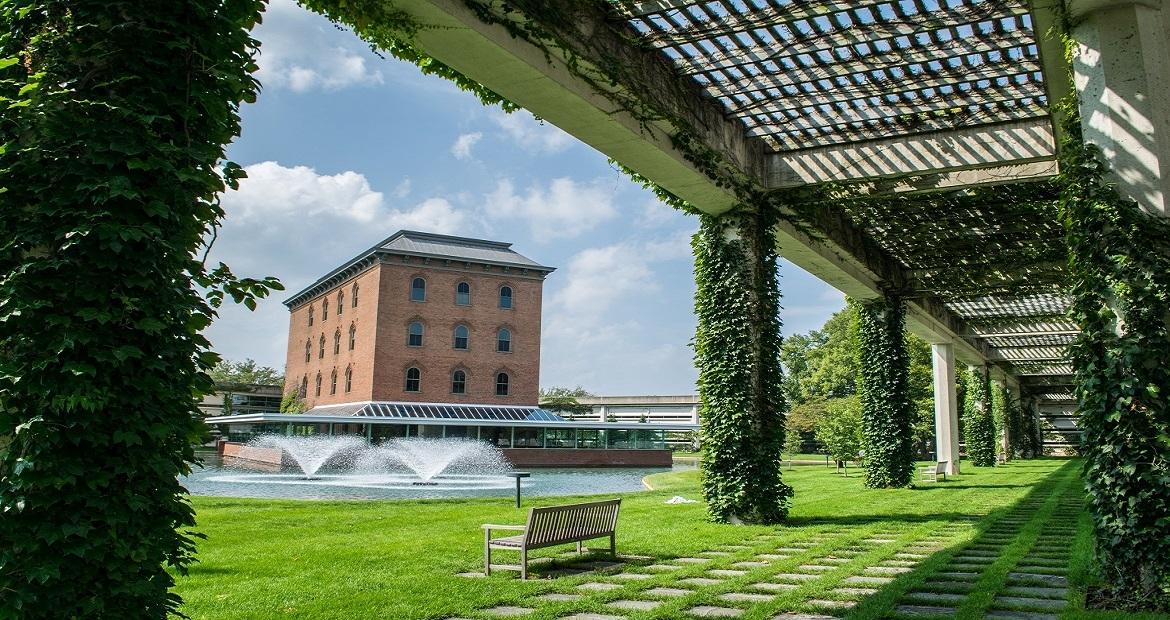 A photo of a building from a distance, which has water fountains in front 