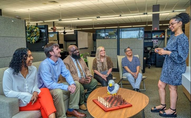 Dedicated customer care specialists from Aflac’s new cancer line discuss ideas to best serve policyholders calling in with a cancer diagnosis. From left, Jazmin Upshaw, Joseph Cosey, Johnny Richmond (supervisor), Mallorie Snethen, Ruth Hill and Deja Zullo (standing). " "