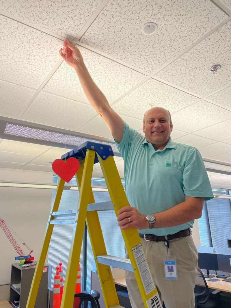 Carl Rohs hanging a red heart from the ceiling.