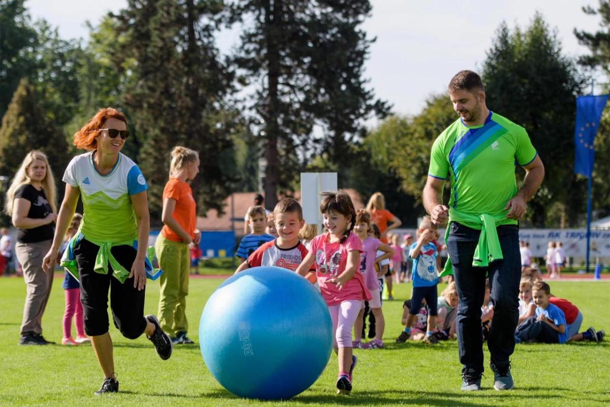 Children playing outside, chasing a large blue ball