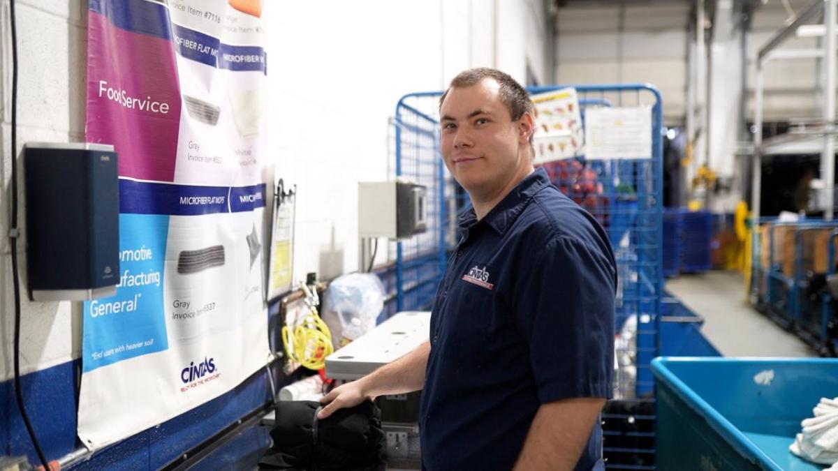 Cintas employee standing in foreground of factory