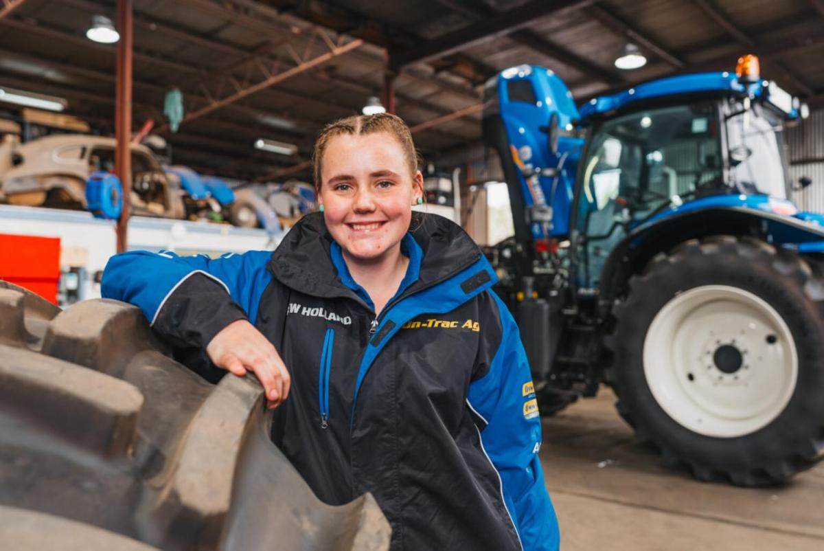 Claire Miller Standing in front of a large tractor.