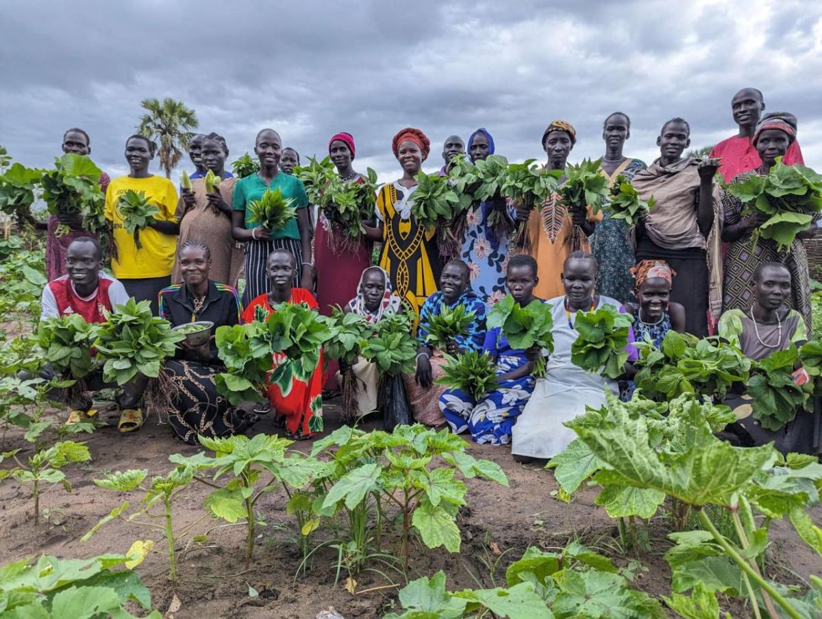 Women hold produce in the community gardnen.