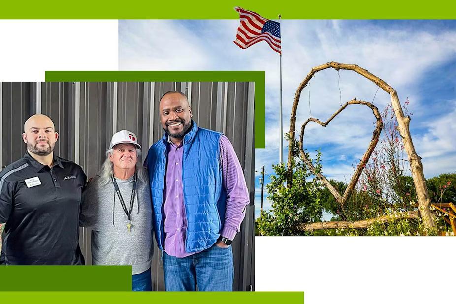 Three people with arms around each other. On the right A wooden heart hanging in an arch, an american flag on a pole next to it.