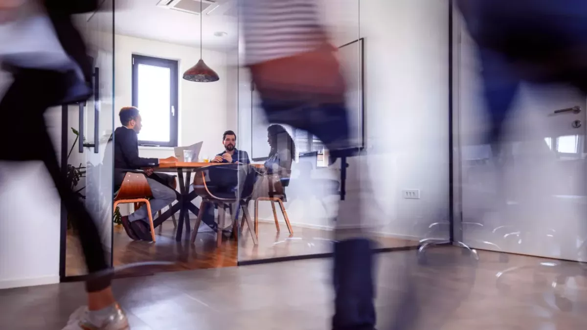 Three people sat around a table in an office