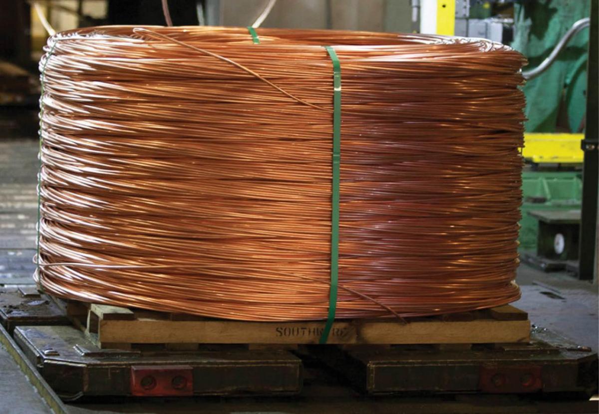 A large bale of coiled copper wire on a pallet in a warehouse.
