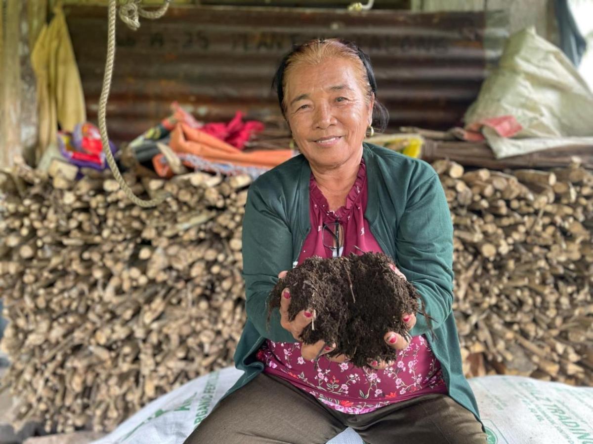 Corazon Malano, 72, a coconut farmer holding up soil