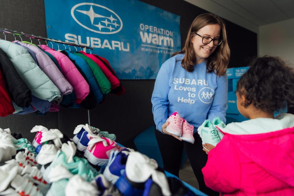 Volunteer handing shoes to child