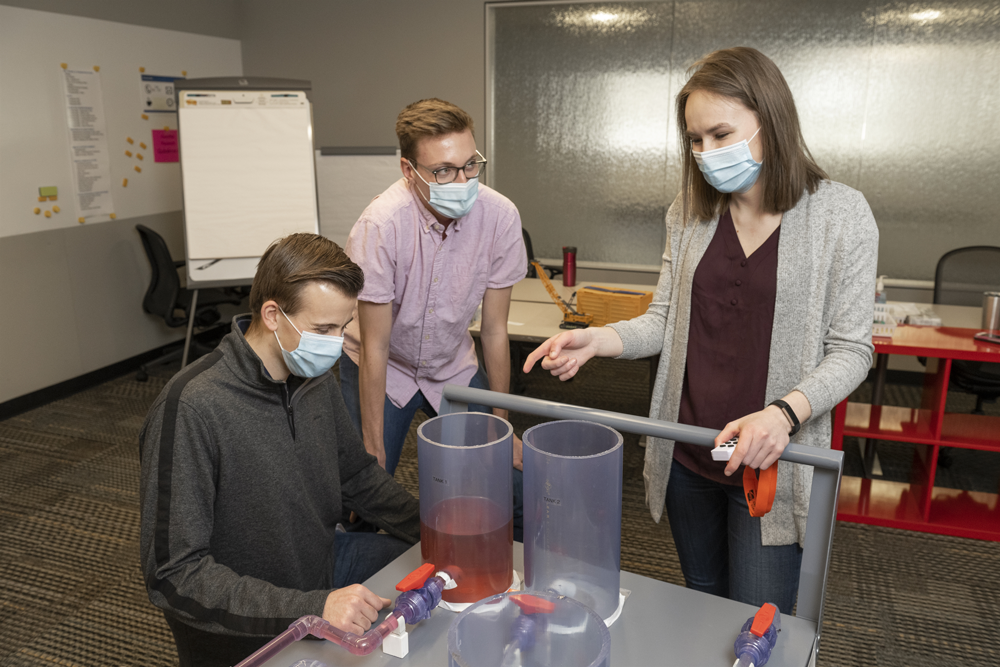 The model uses dyed water to simulate a pipeline cut and fill different tanks from a manifold.