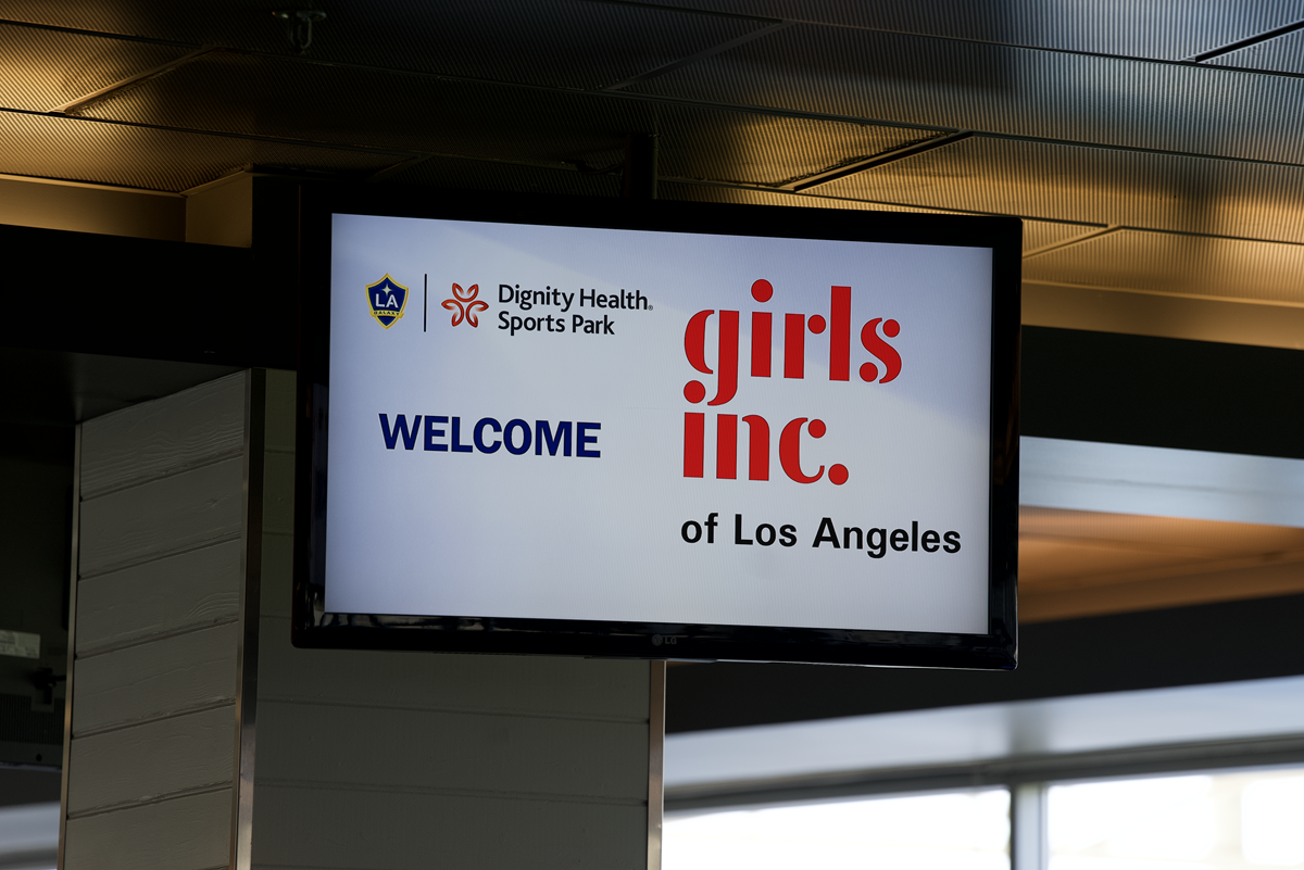 Digital welcome sign at Dignity Health Sports Park displaying LA Galaxy and Girls Inc. of Los Angeles logos ahead of a youth empowerment event.