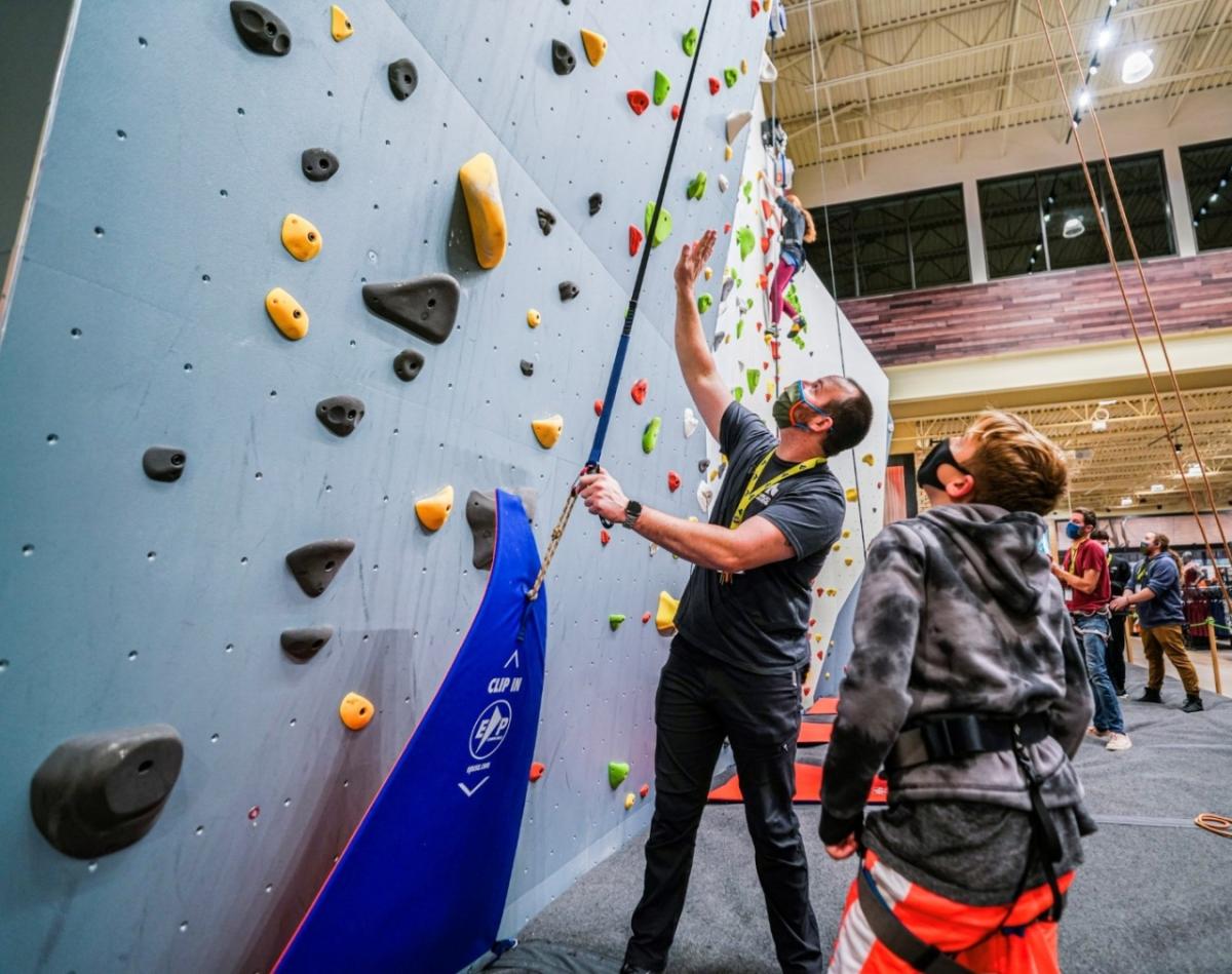 Jesse Kindelberger helps a young explorer navigate the climbing wall at Public Lands.