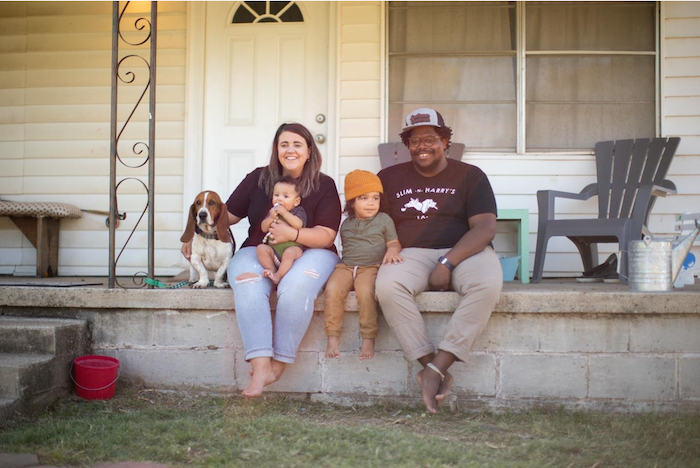 Jahmicah and Heather Dawes seated on their front porch with their two children and dog.