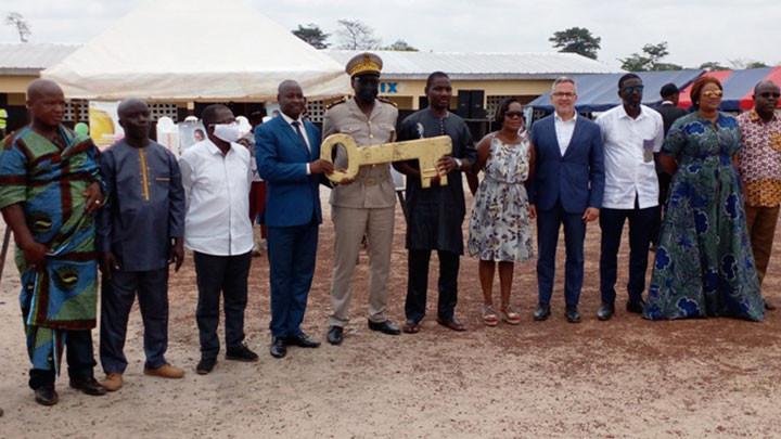 group of people stand in a line. A few hold a giant key