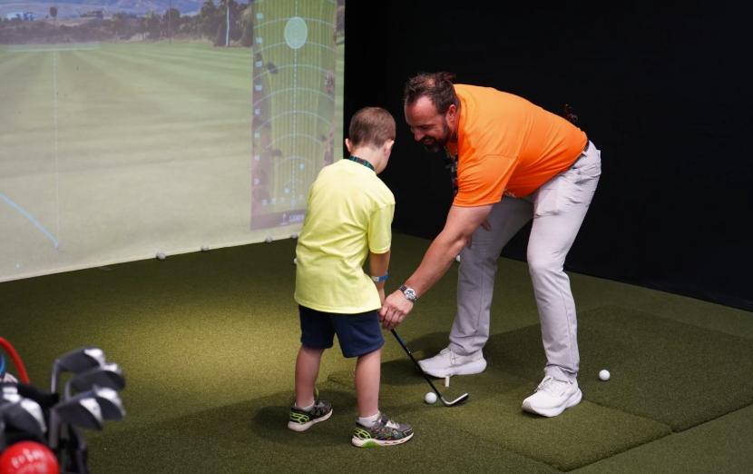 A young golfer receiving lessons from a pro.