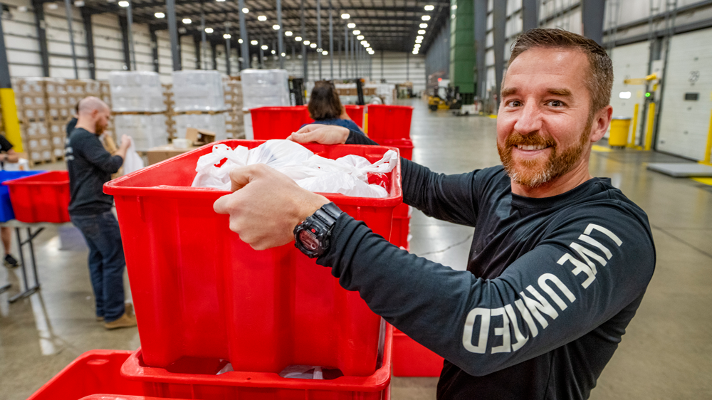 Person lifting up a red bin inside a warehouse building