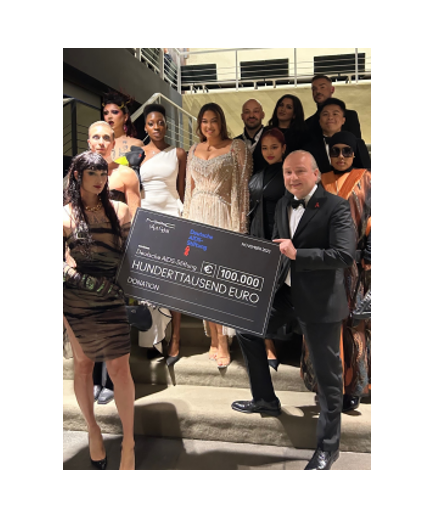 A group posed on a staircase, two holding a large check.