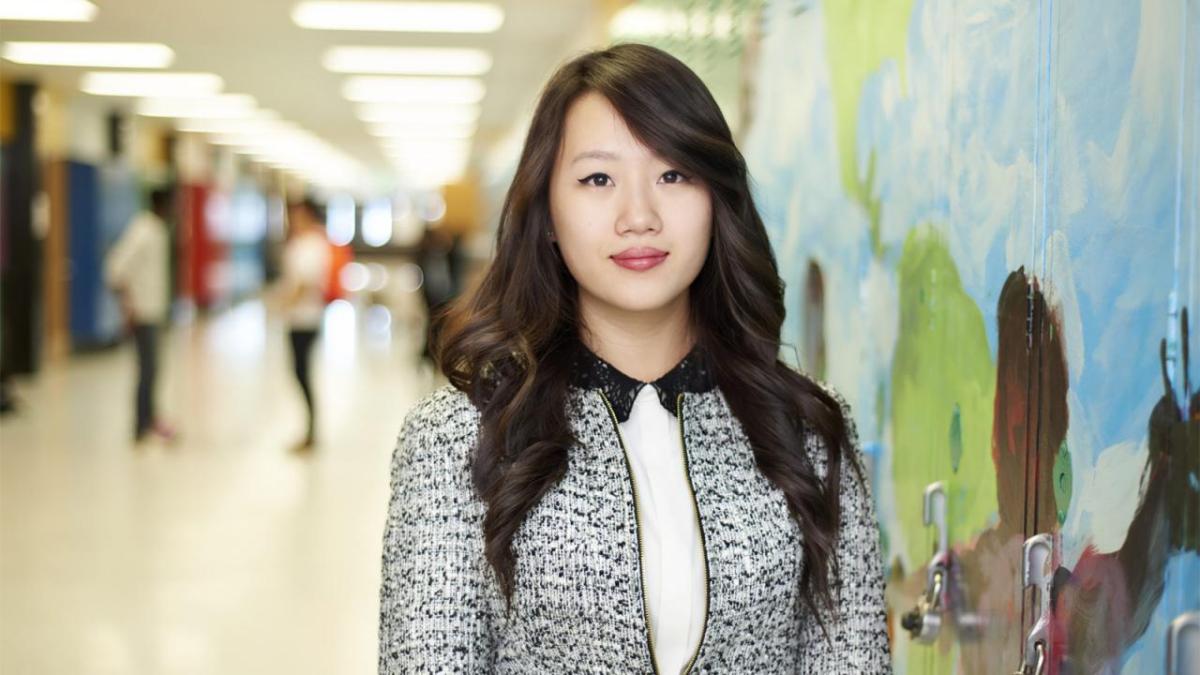 One person standing in a hallway in front of painted lockers