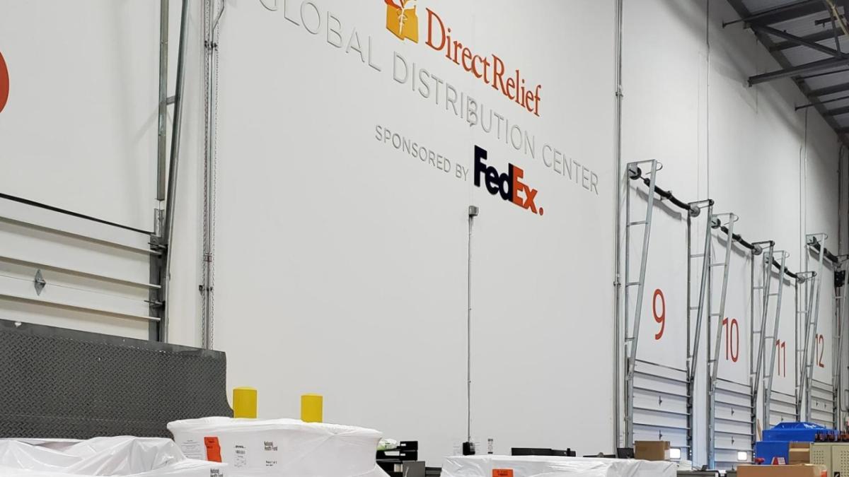 Large bay doors, "DirectRelief Global Distribution Center sponsored by FedEx" on the wall.