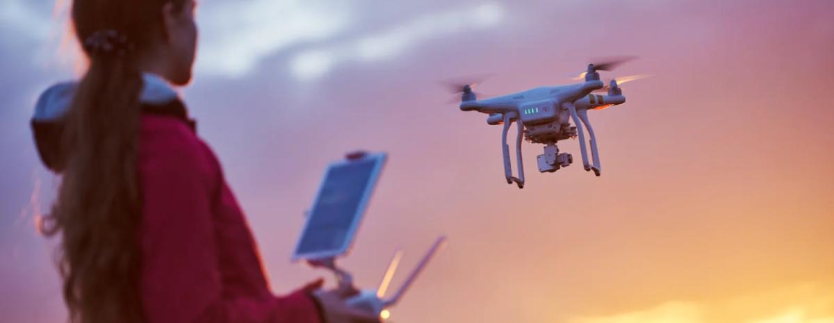 a person flys a drone, sun setting in the background