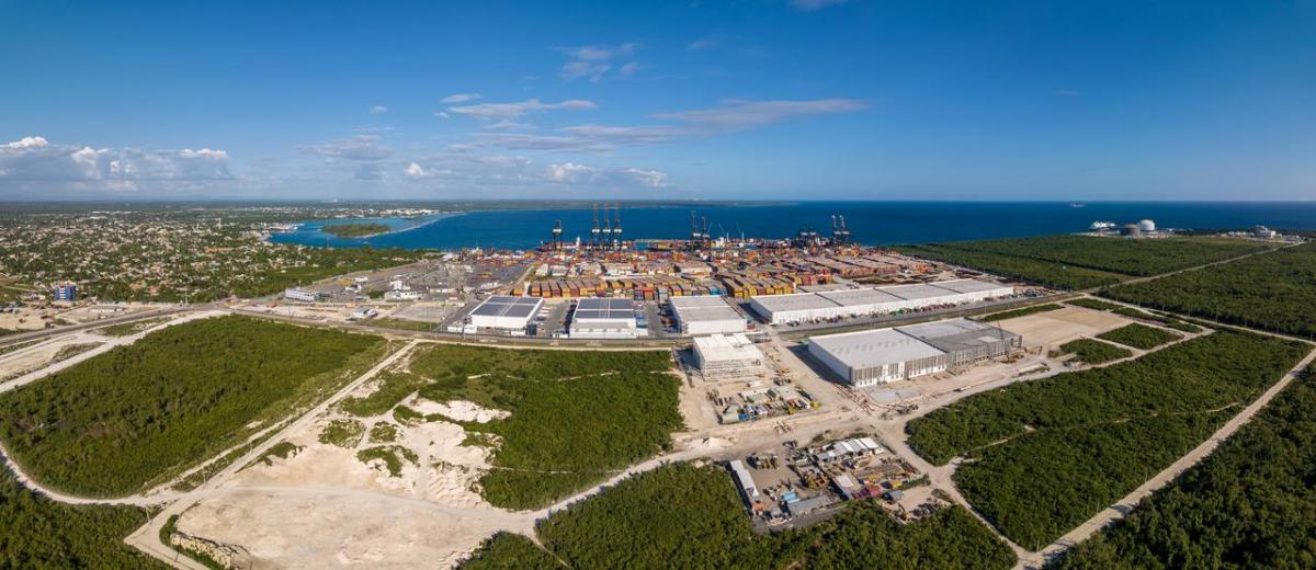 An expansive aerial view of DP World’s Caucedo Port and Special Economic Zone in the Dominican Republic, showing container yards, cranes, logistics warehouses, and surrounding greenfield development along the coastline.