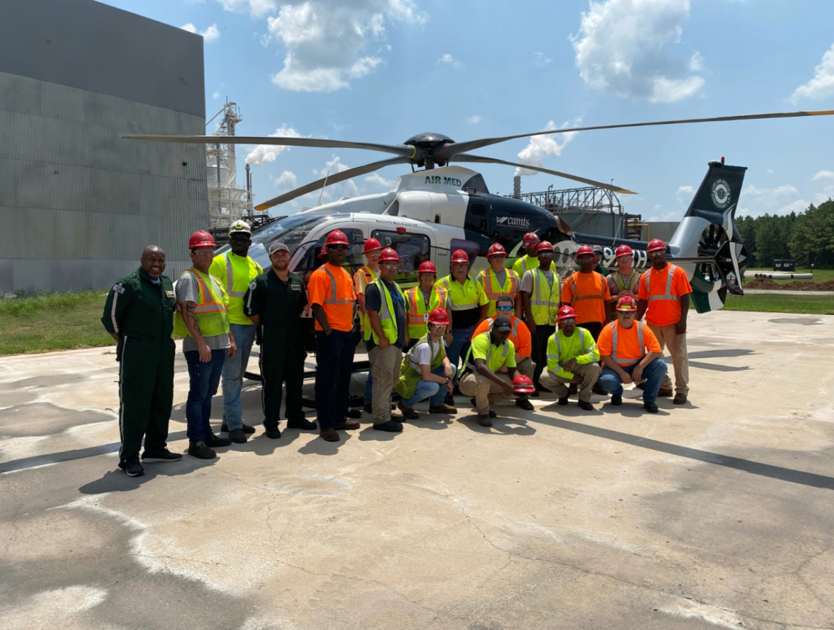 A group of people posing for a photo in front of a helicopter