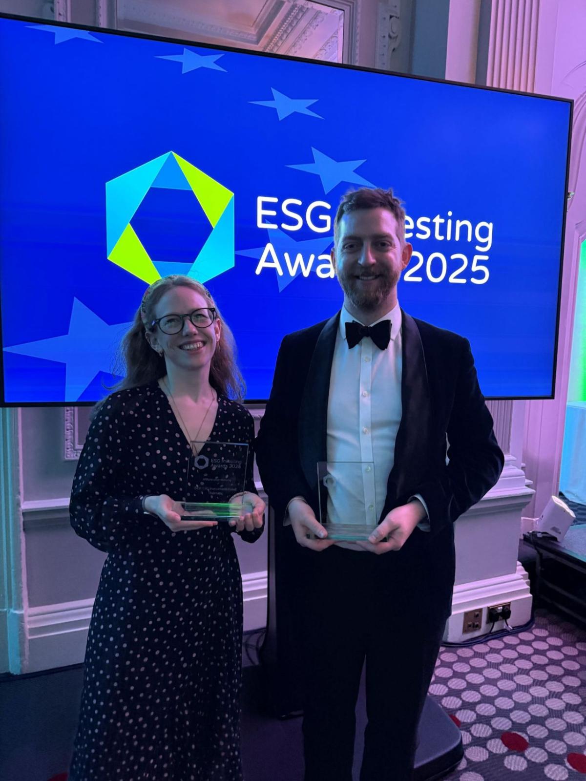Two people, each holding an award, in front of a screen reading "ESG Investing Awards 2025"