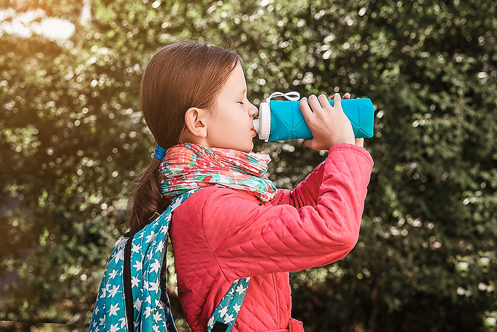 Young girl sipping a water bottle.