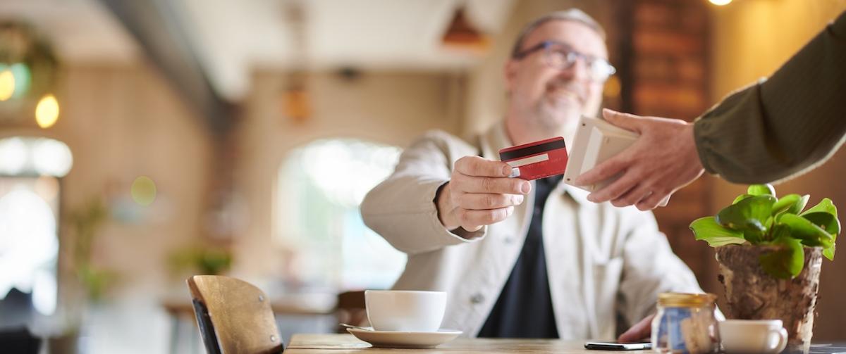A man shown having coffee and paying with a credit card.